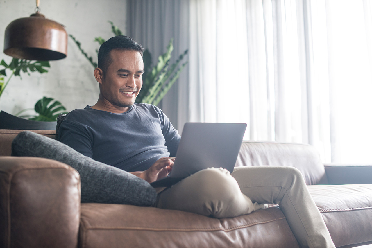 Young-Asian-man-working-at-home on his laptop.